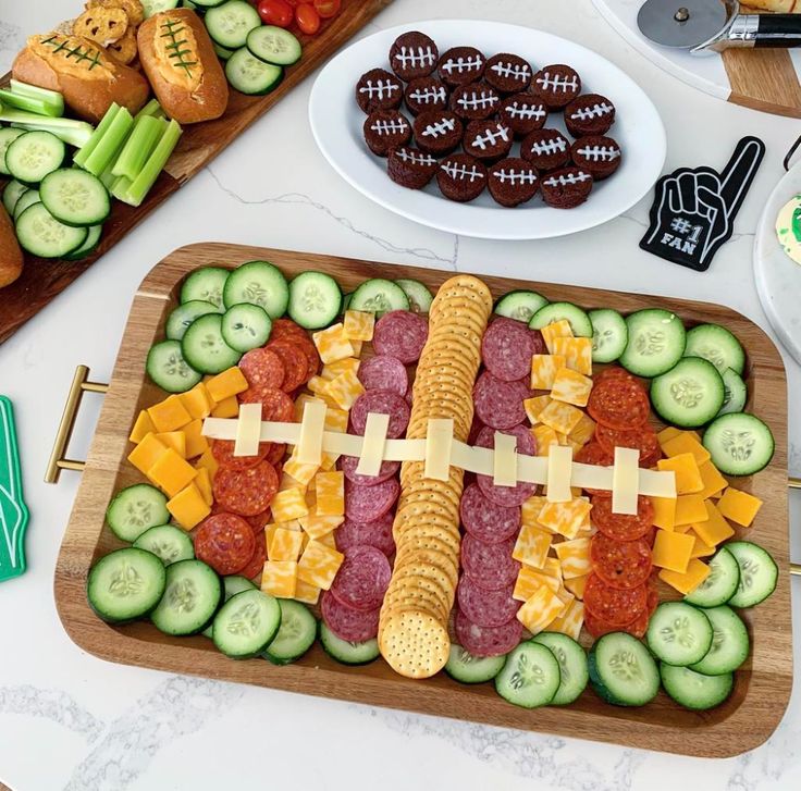 a platter filled with cucumber, cheese and meats next to other snacks