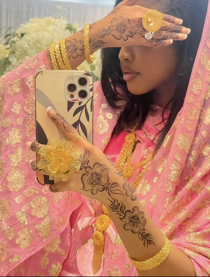 a woman with henna on her hand holding up a cell phone