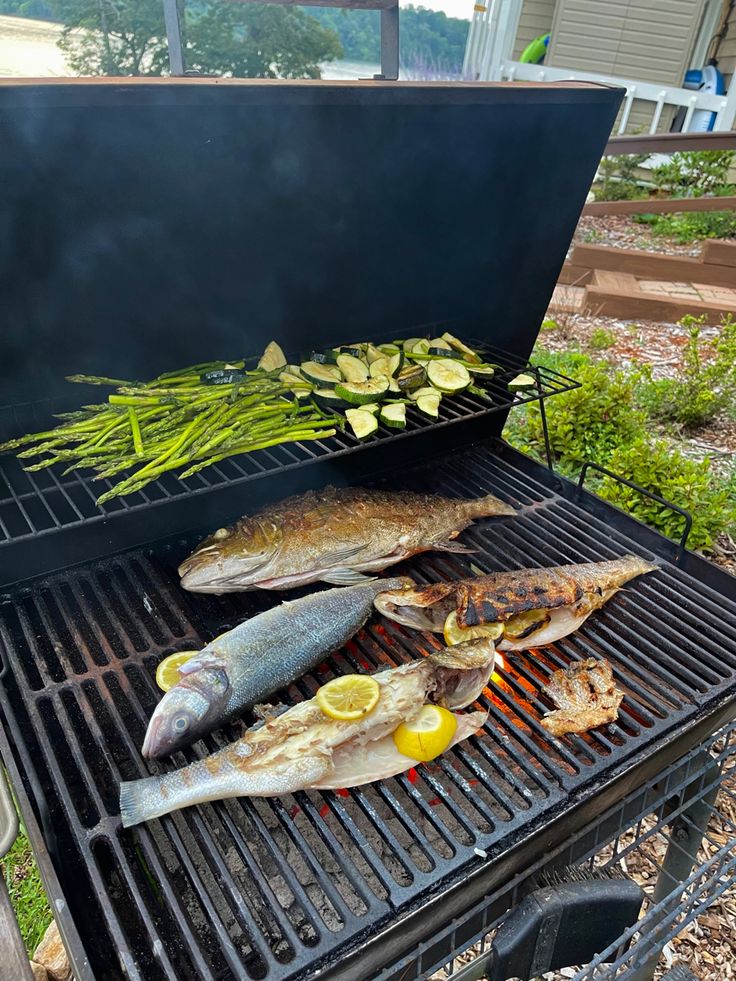 fish and vegetables are cooking on the grill