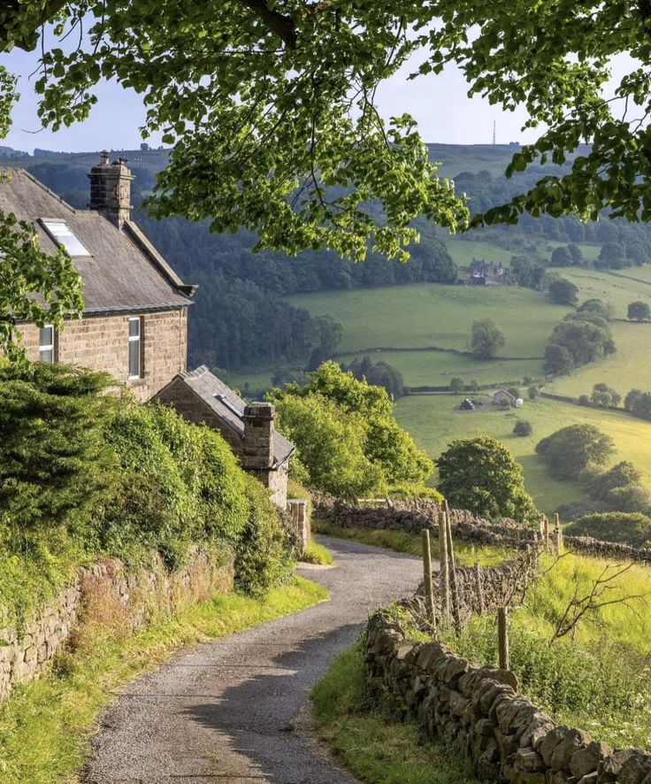 an old stone house in the countryside with green fields and rolling hills behind it, on a sunny day