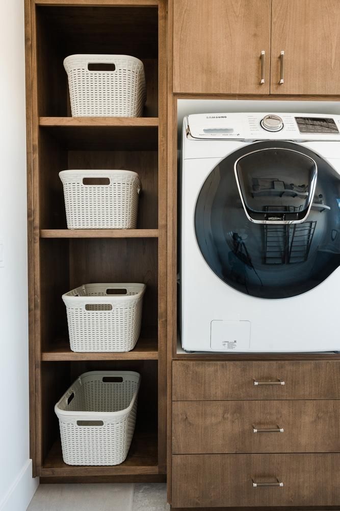 a washer and dryer sitting in a room next to some shelves with baskets