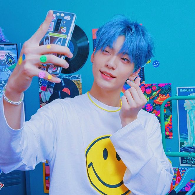 a young man with blue hair holding up a cell phone in front of his face