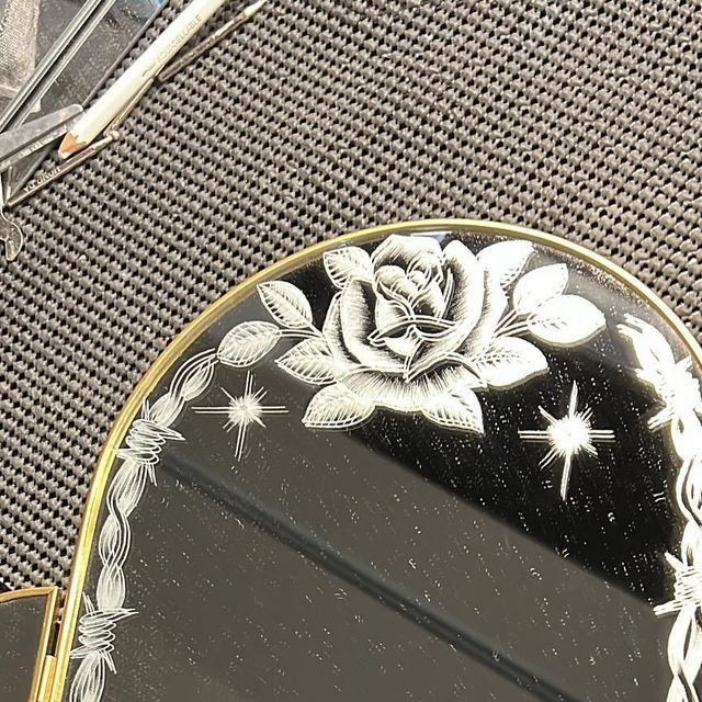 there is a mirror with a flower on it next to scissors and other things in front of it