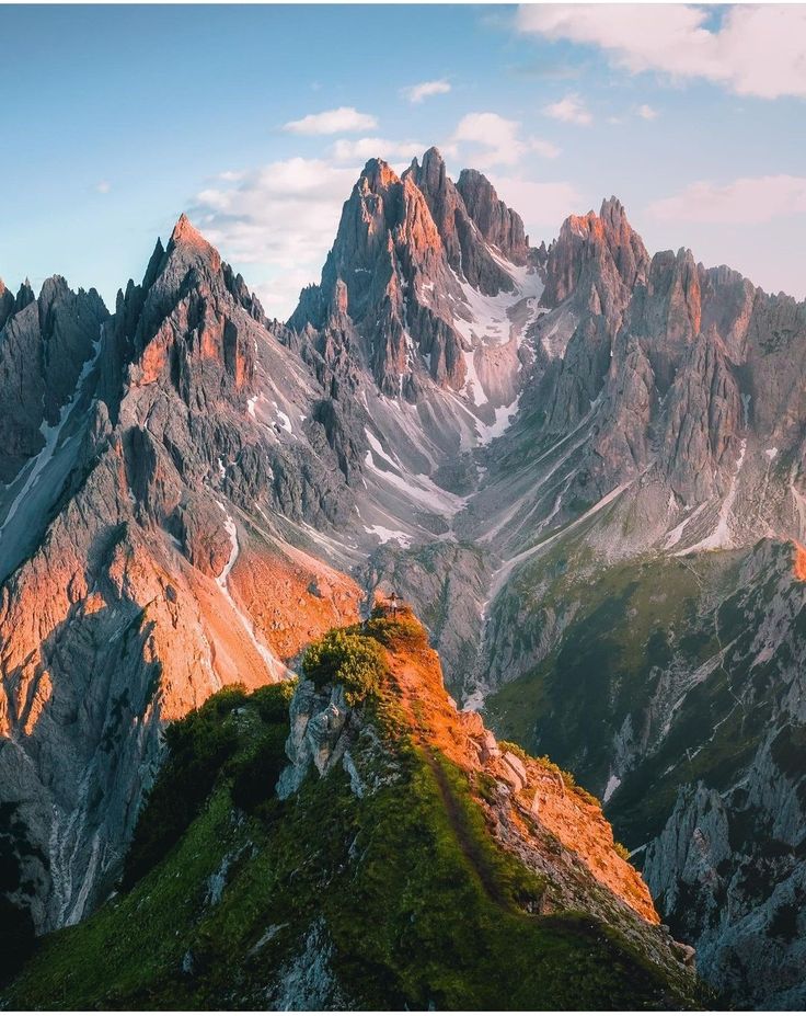 the mountains are covered in snow and green grass