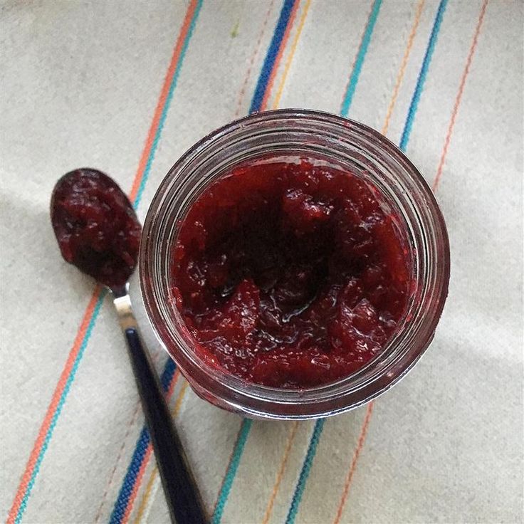 a glass jar filled with jam sitting on top of a table next to a spoon