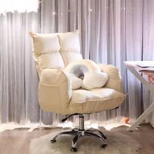 an office chair with pillows on it in front of a curtained wall and desk