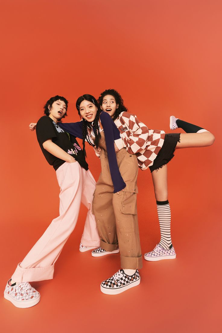 three young women are posing for the camera with their arms around each other and one woman is holding her leg up