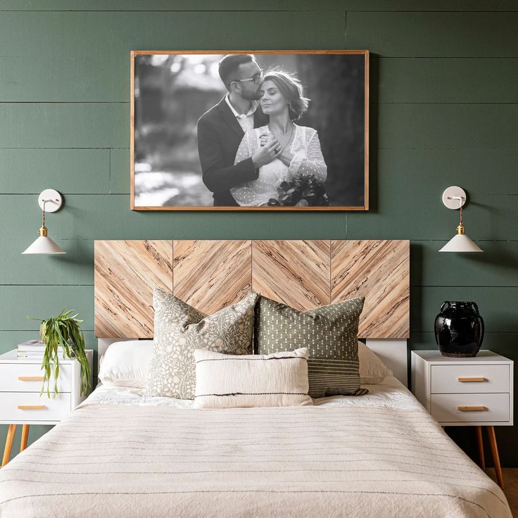 a bedroom with green walls and white bedding has a large photo on the wall