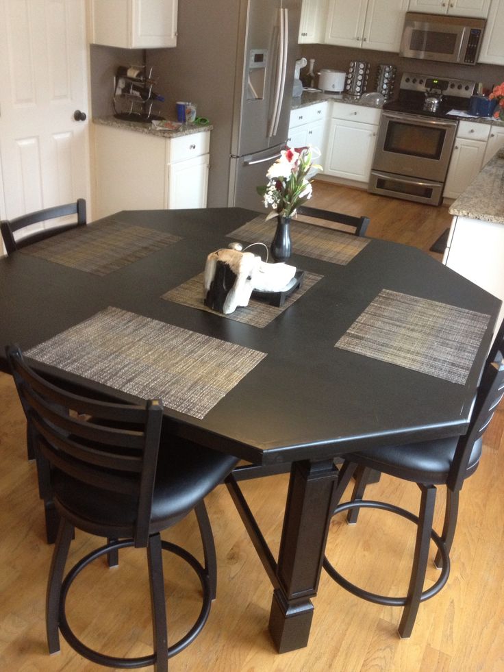 a kitchen table with four chairs and a vase on the center island in front of it