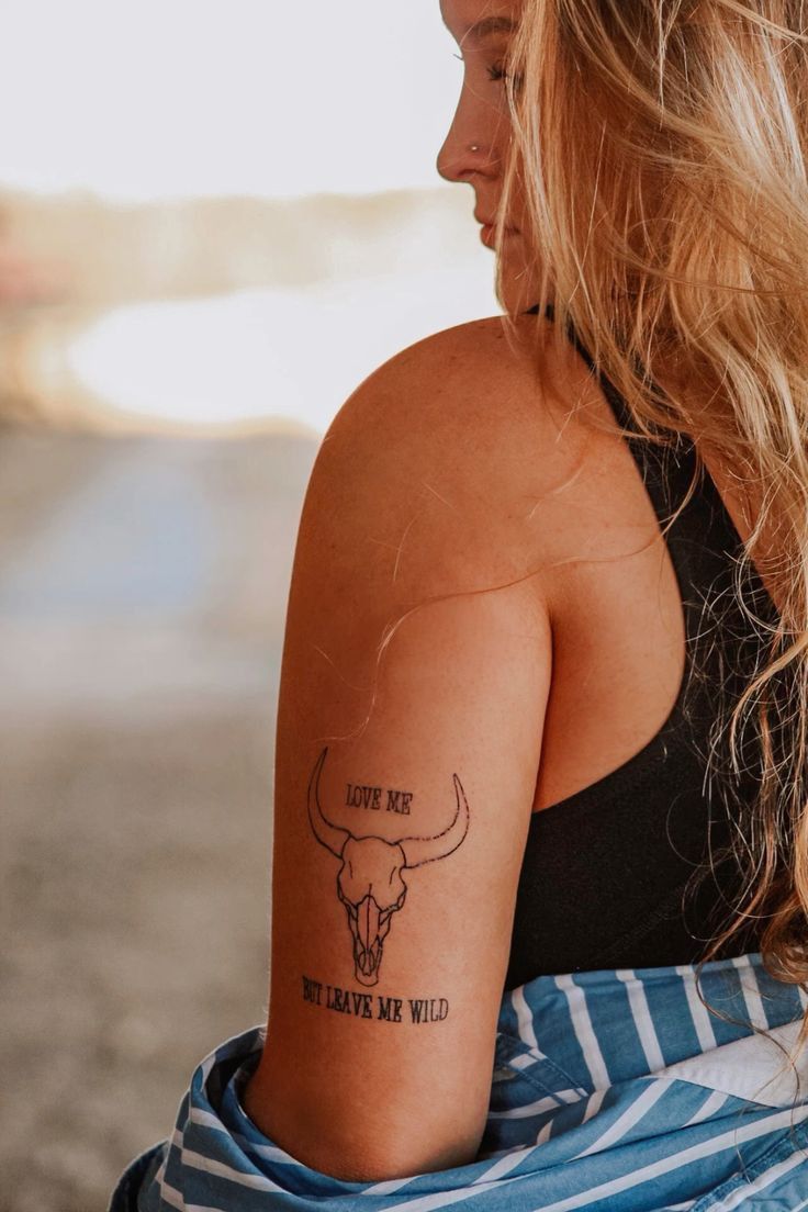 a woman with a cow skull tattoo on her arm and the words, you're not