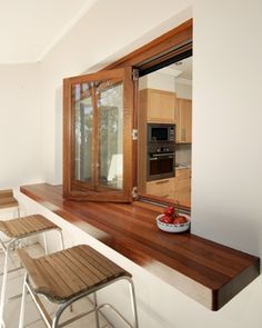 a kitchen with wooden counter tops and stools next to an open window on the wall