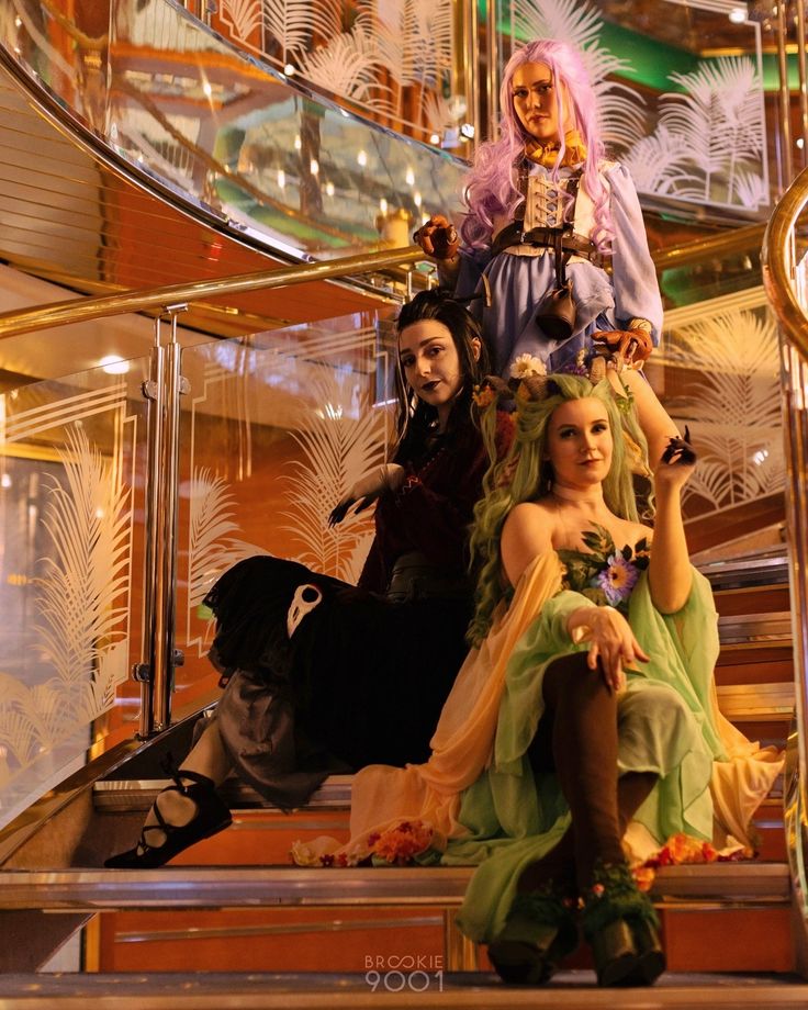 three people dressed up as princesses sitting on the steps in front of a staircase