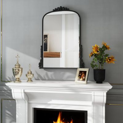 a white fireplace with a mirror above it