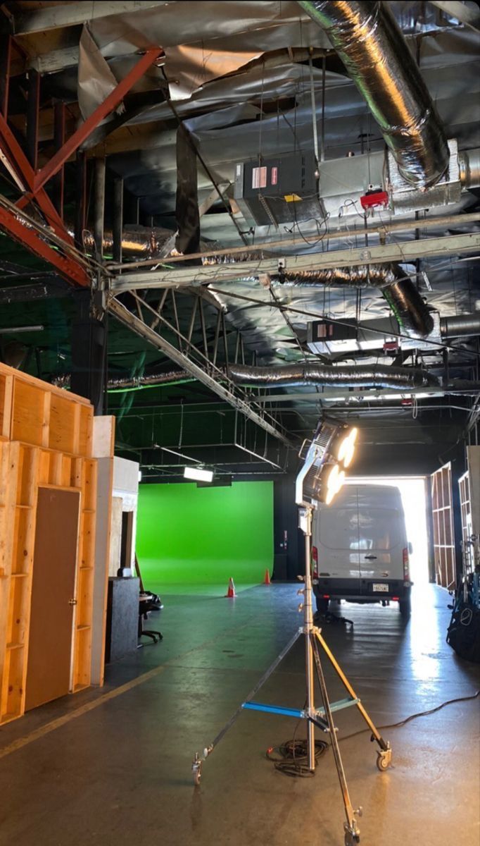 the interior of an empty building with green screen and lighting equipment in front of it