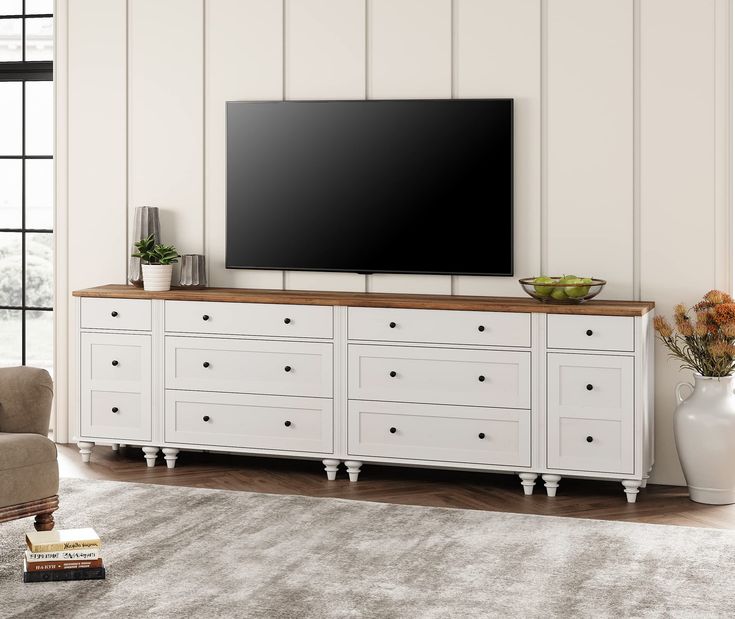 a large flat screen tv mounted to the side of a white cabinet in a living room