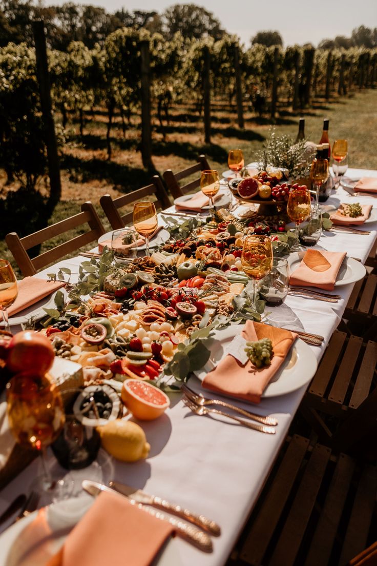 a long table is set with plates and utensils for an outdoor dinner party