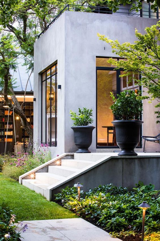 a modern house with large planters on the front and stairs leading up to it