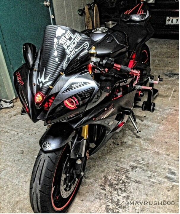 a black motorcycle parked in front of a garage door with graffiti on the side and red accents