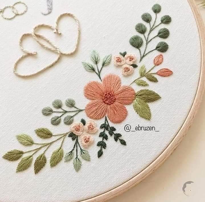 a close up of a embroidery on a hoop with flowers and hearts in the background