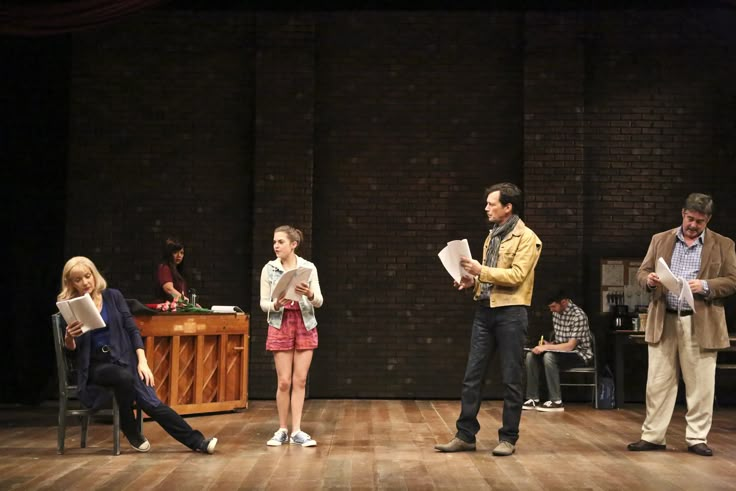 three people standing on a stage with papers in their hands