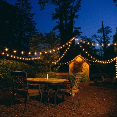 an outdoor dining area with lights strung over it