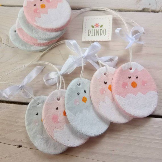 five little pink and white birds hanging from strings on a wooden table with a tag that says dino