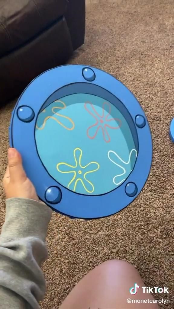 a child is playing with a blue and yellow plate on the floor in front of a couch