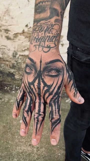 a man with tattoos on his hand and face is holding onto the palm of his hand