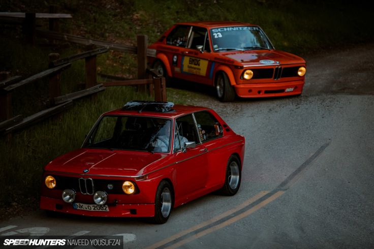 two red cars driving down a road next to each other