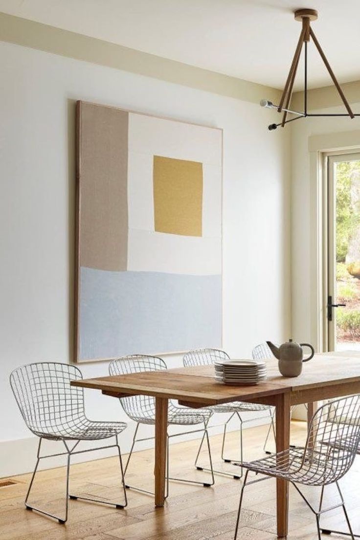 a dining room table with chairs and a teapot on it in front of a window