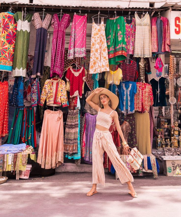 a woman standing in front of a store filled with colorful clothing