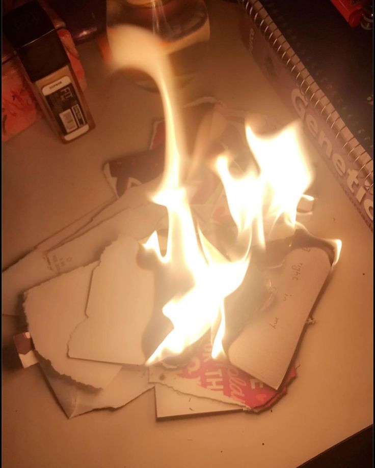 a pile of papers sitting on top of a table covered in fire and flames next to a cell phone