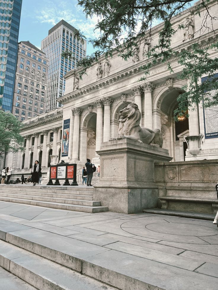 people are walking around in front of a building with columns and statues on the steps