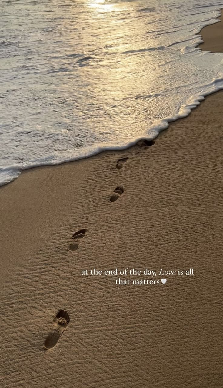 footprints in the sand leading into the ocean with a quote written on it that reads at the end of the day, love is all that matters