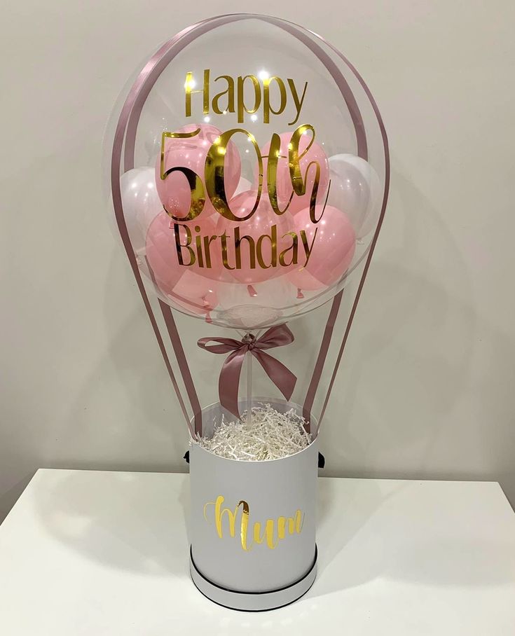 a birthday balloon with pink and gold balloons in a gift box that says happy 50th