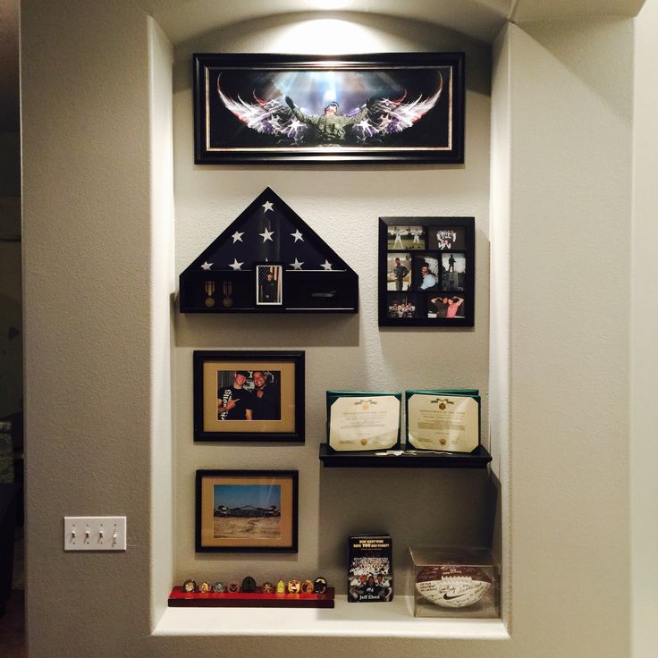 a wall with several framed pictures and other items on it's sides, including an open book shelf