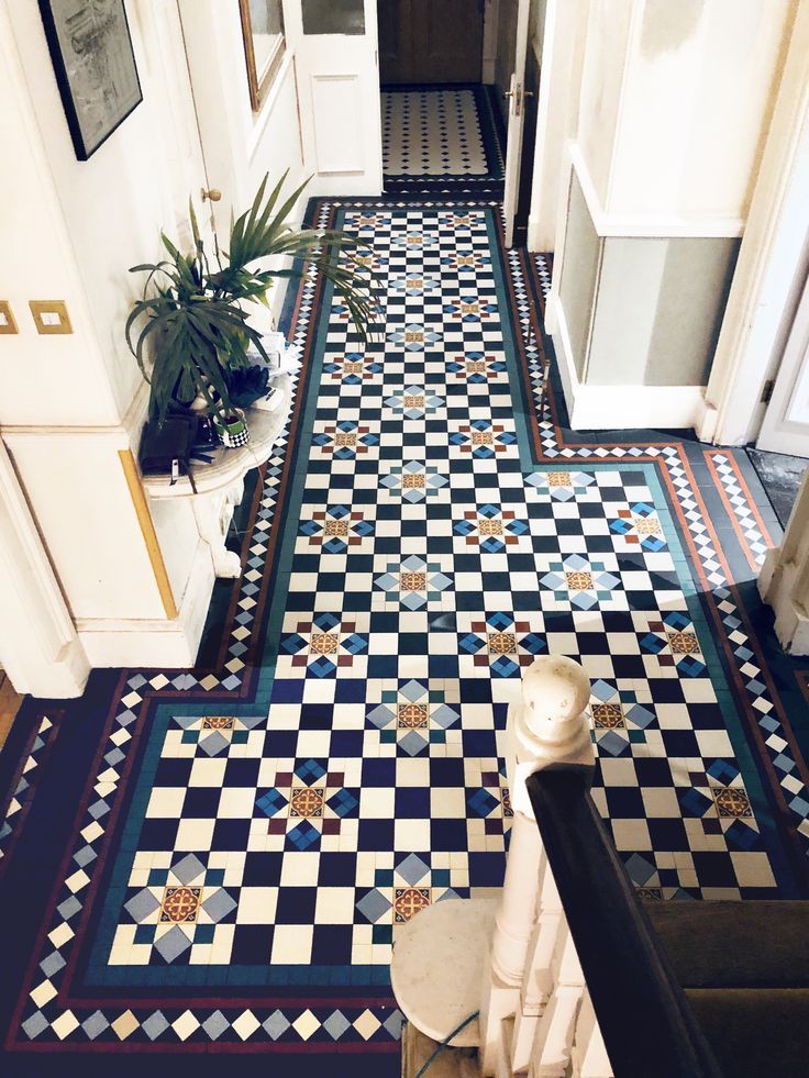 a hallway with black and white checkered flooring, potted plant on the stairs