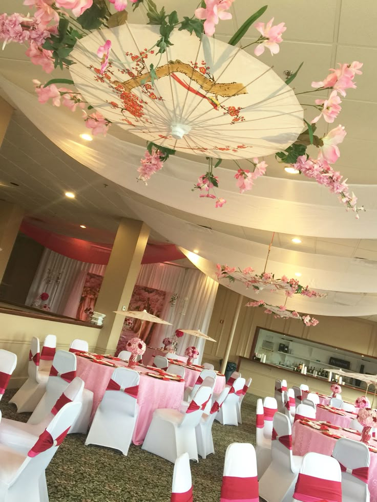 the banquet hall is decorated with pink and white linens, flowers, and umbrellas