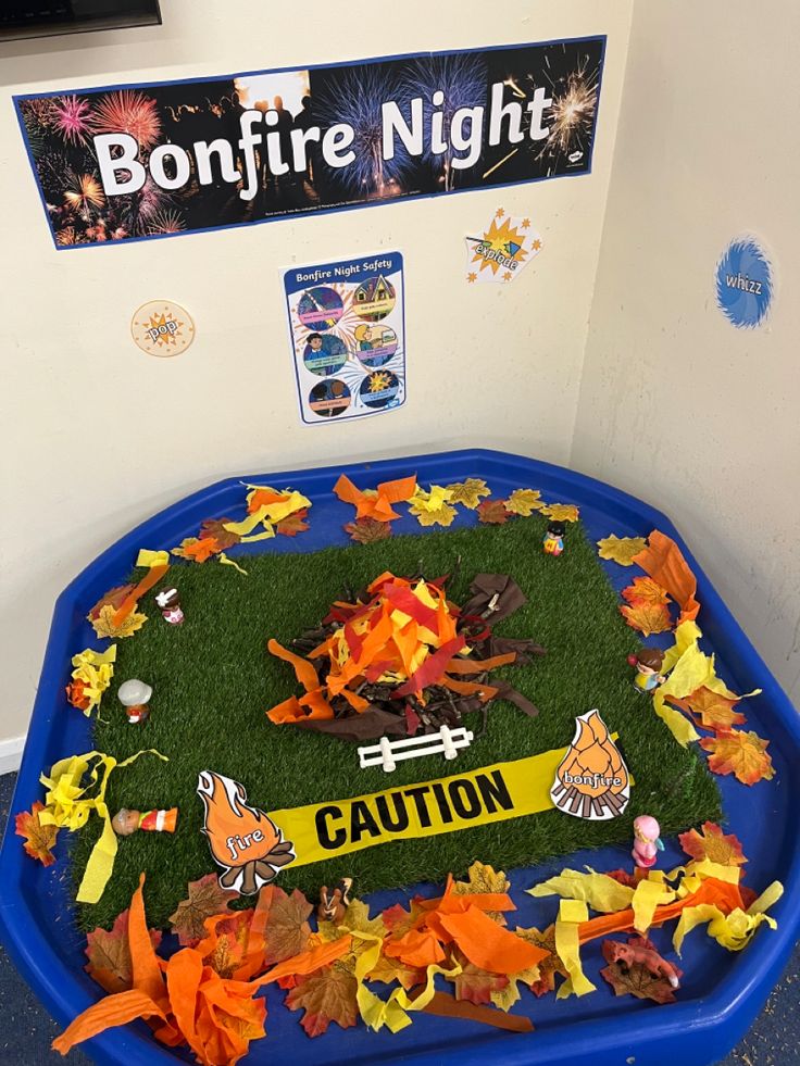 an artificial lawn with fake leaves on it in a blue container that reads bonfire night caution