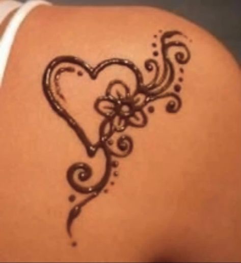 the back of a woman's shoulder with a heart and flower tattoo on it