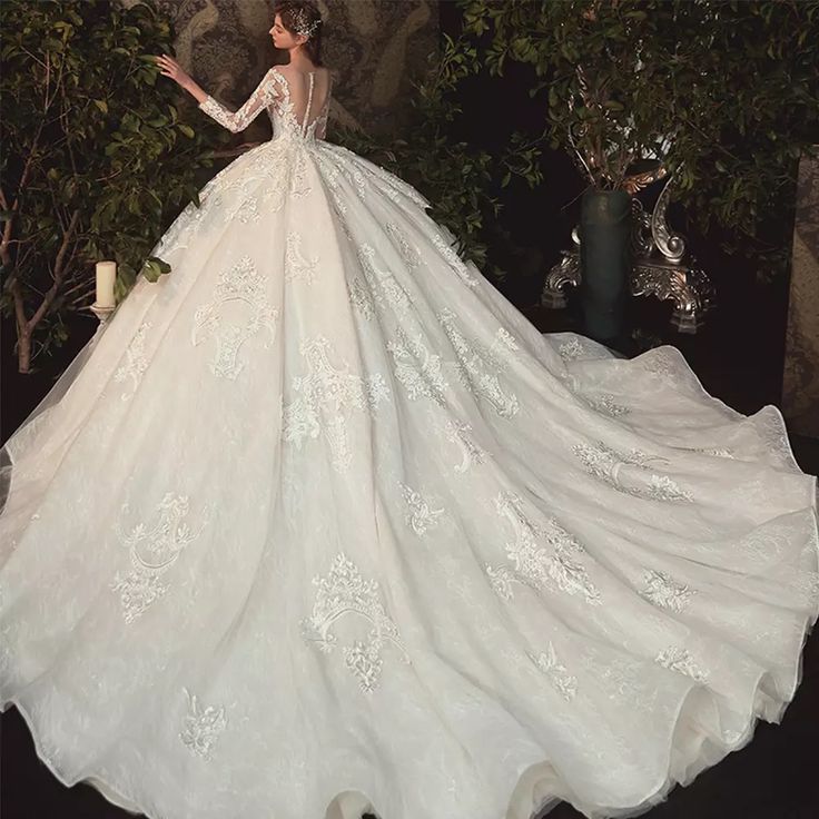 a woman in a white wedding dress standing next to a tree with flowers on it