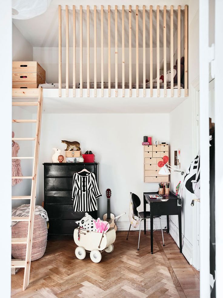 a room with a loft bed, desk and ladder in the corner next to it