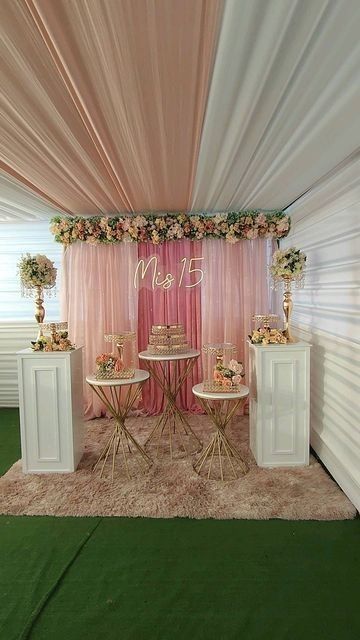 a decorated stage with pink drapes and gold chairs for the bride and groom to sit on