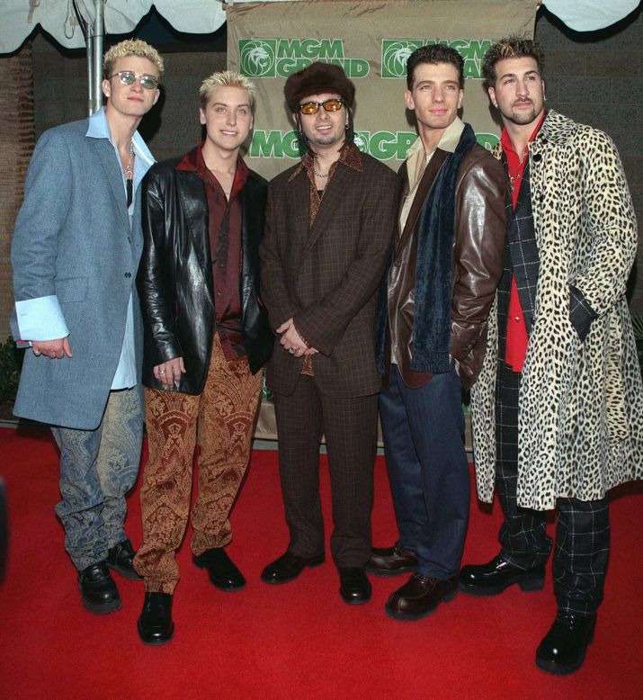 four men standing next to each other on a red carpet