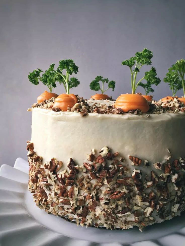 a cake decorated with carrots, nuts and parsley on a white platter