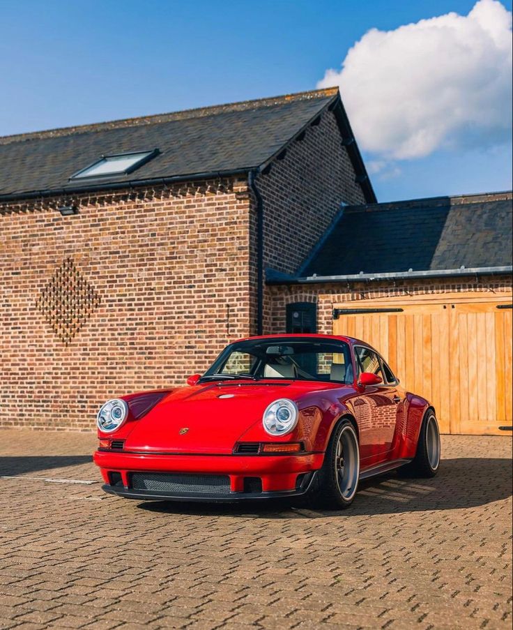 a red porsche parked in front of a brick building