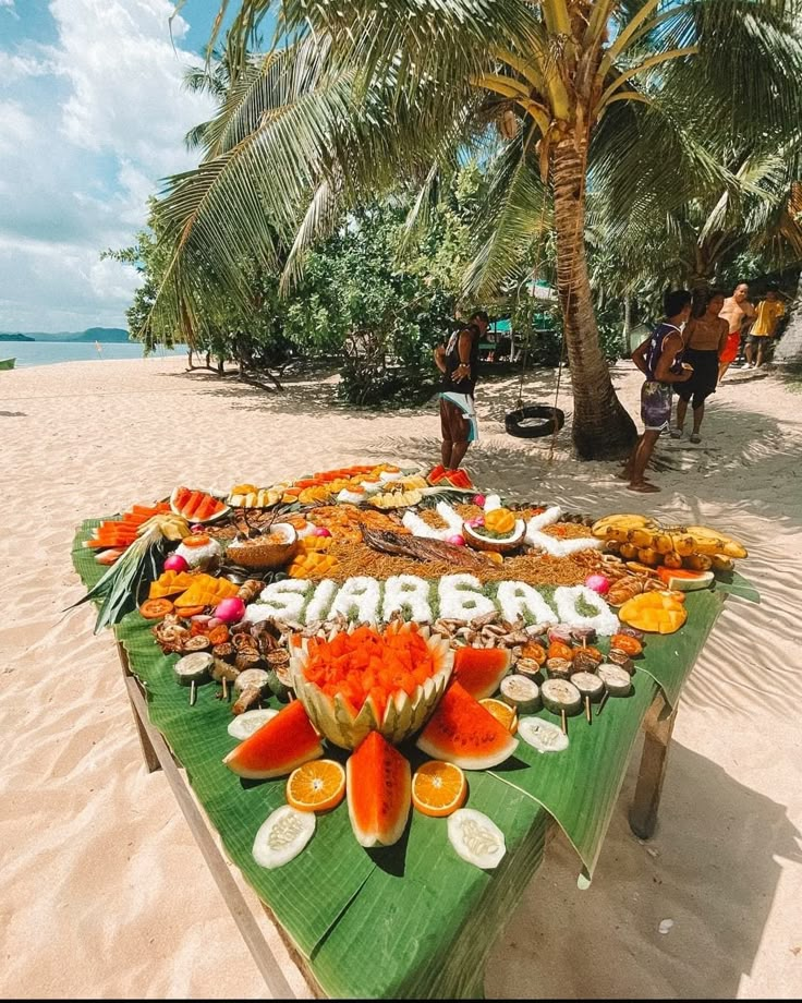 a table on the beach is decorated with food