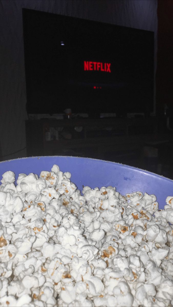 a blue bowl filled with popcorn sitting on top of a table