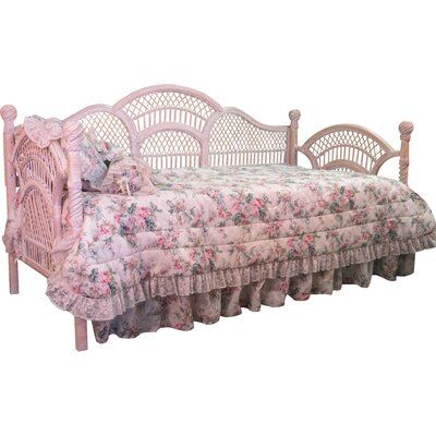 a white daybed with pink flowers and ruffled bedspread on the bed