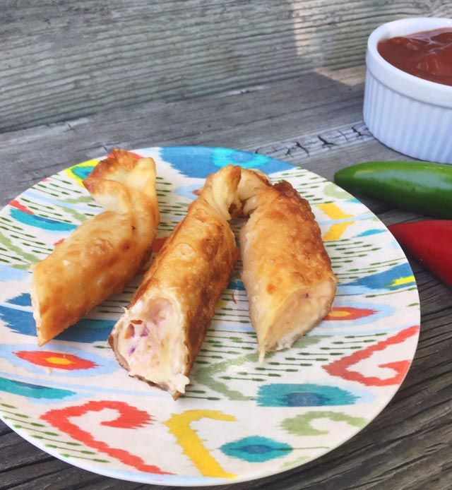 a plate with some food on it next to a bowl of sauce and two peppers